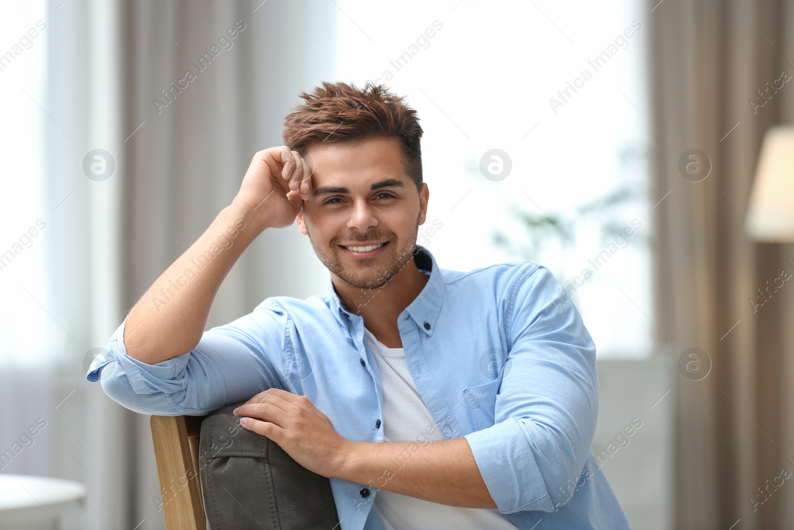 Photo of Portrait of handsome young man sitting on chair in room