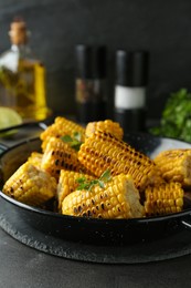 Pan with tasty grilled corn on dark grey table