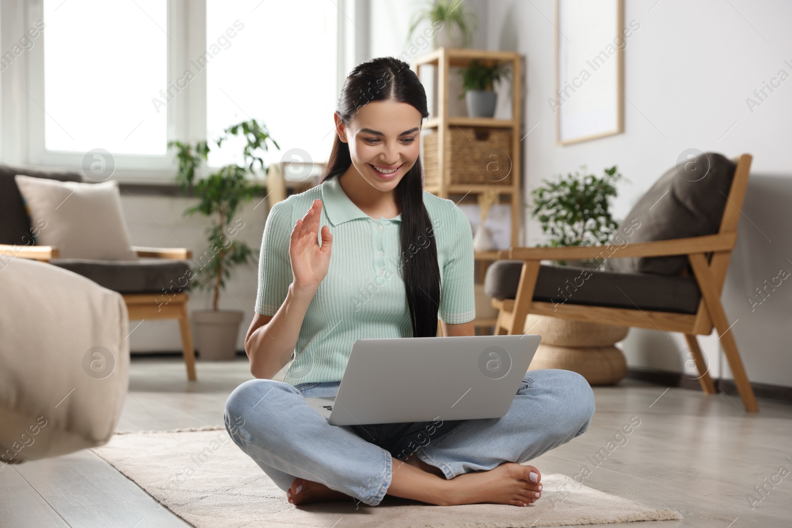 Photo of Young woman having video call on laptop at home