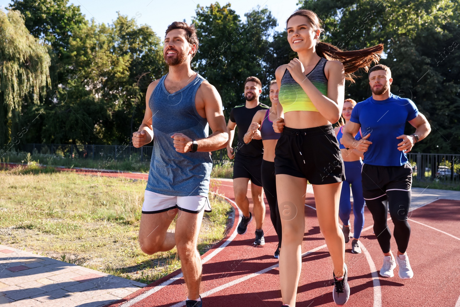 Photo of Group of people running at stadium on sunny day