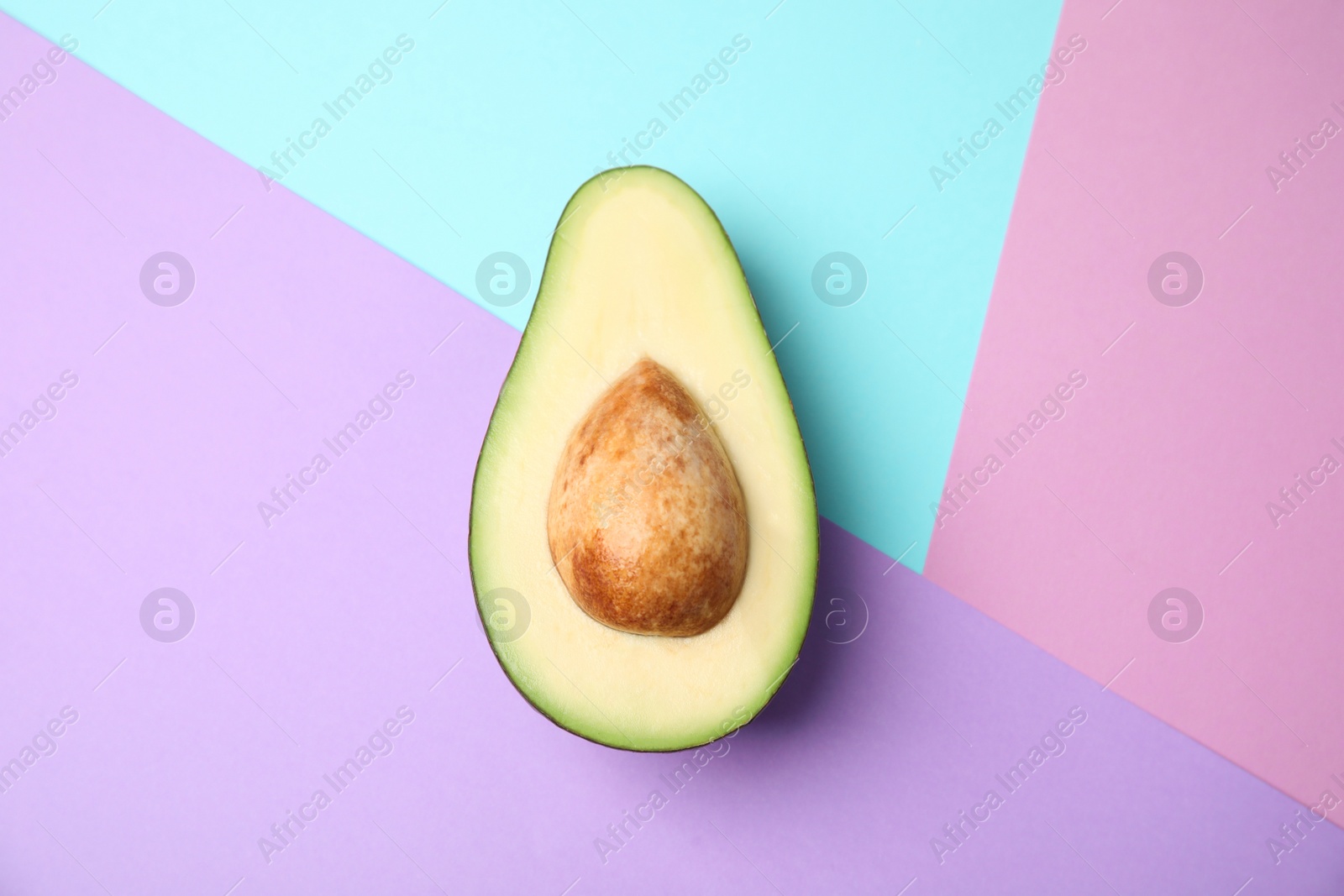 Photo of Cut fresh ripe avocado on color background, top view