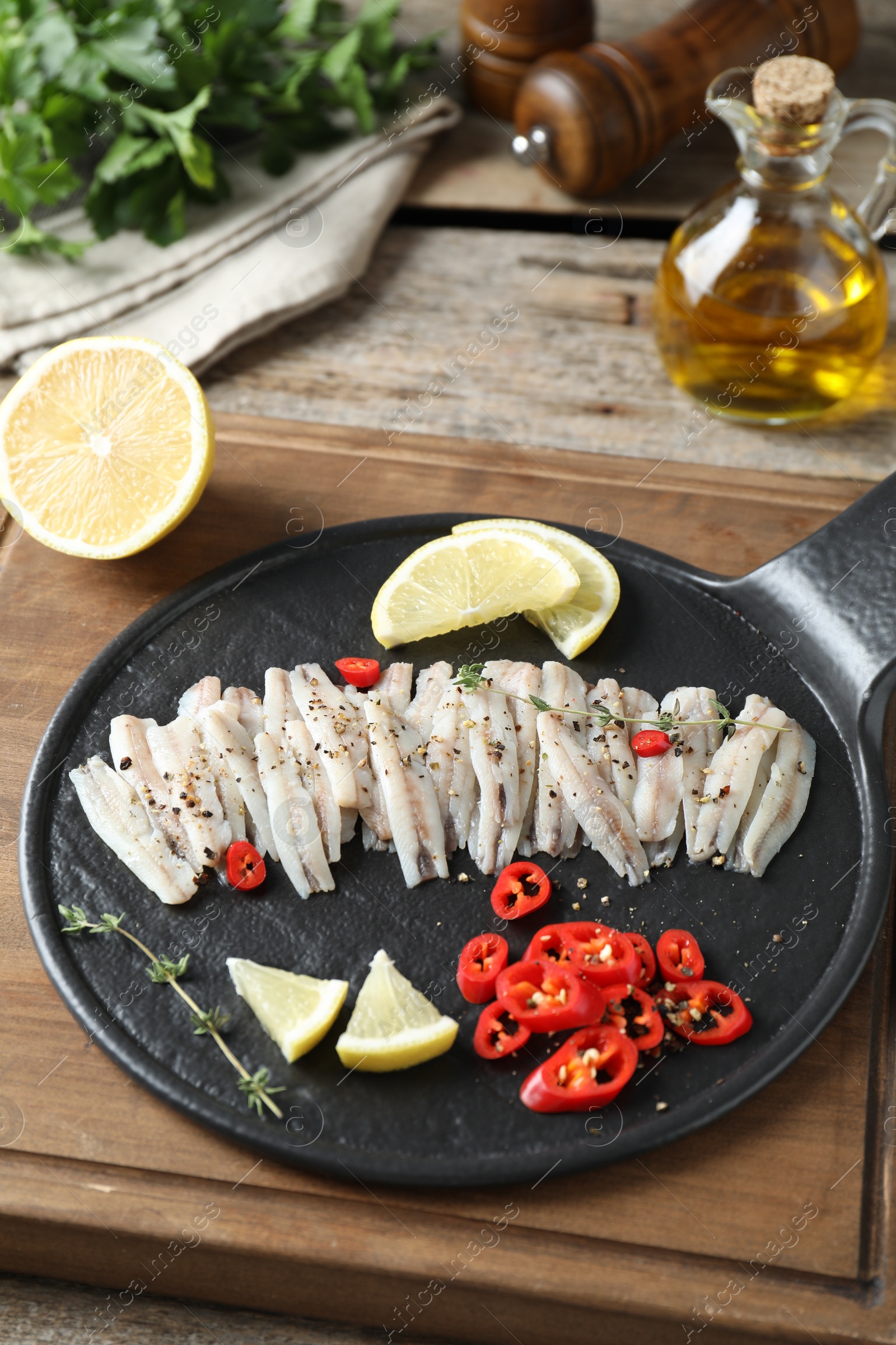 Photo of Tasty anchovies with spices and lemon slices on table