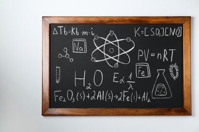 Photo of Blackboard with different chemical formulas written with chalk on white wall