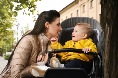 Photo of Happy mother with her son in stroller outdoors