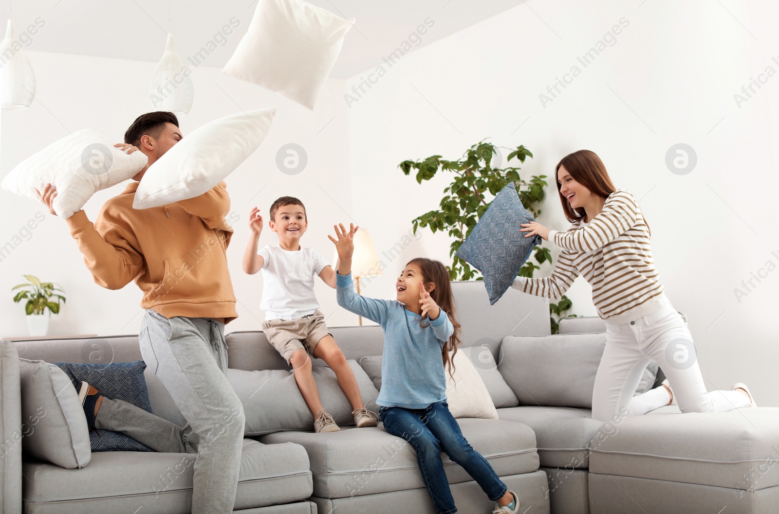 Photo of Happy family having pillow fight in living room