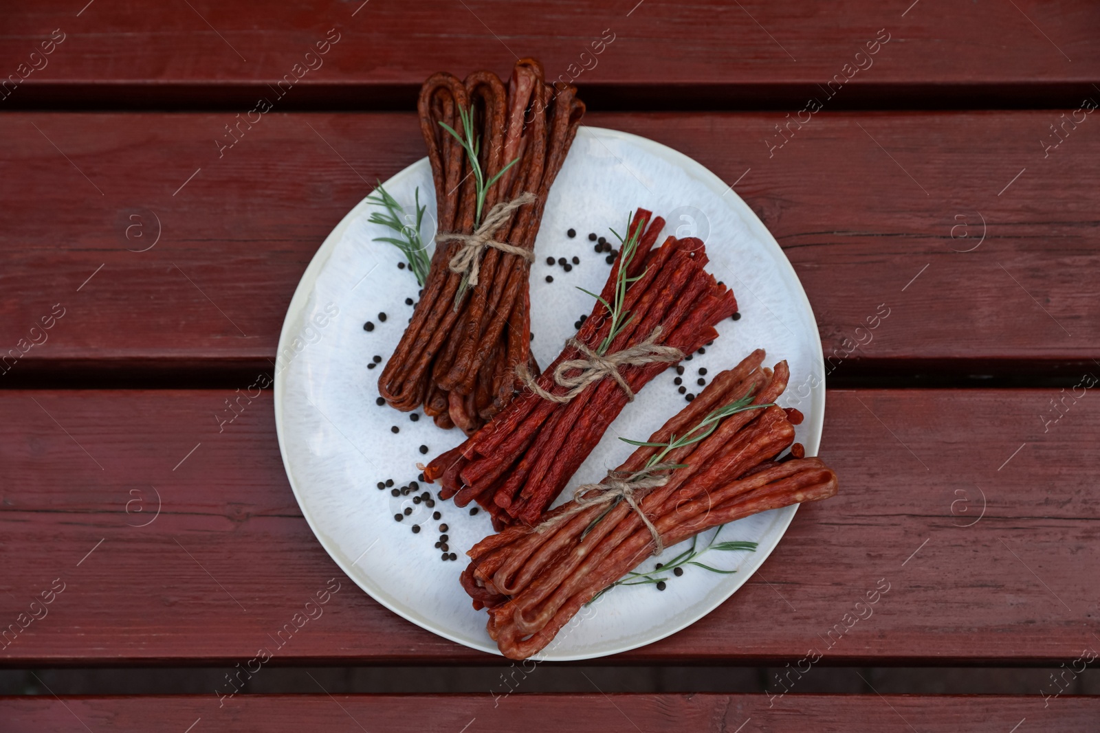 Photo of Tasty dry cured sausages (kabanosy) and spices on wooden table, top view