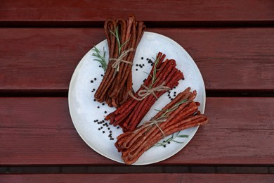 Photo of Tasty dry cured sausages (kabanosy) and spices on wooden table, top view