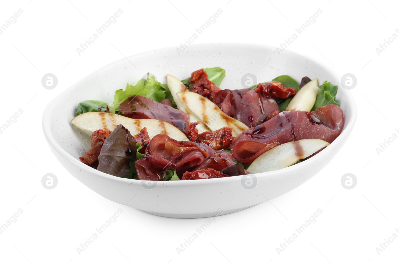 Photo of Delicious bresaola salad with sun-dried tomatoes, pear and balsamic vinegar in bowl isolated on white