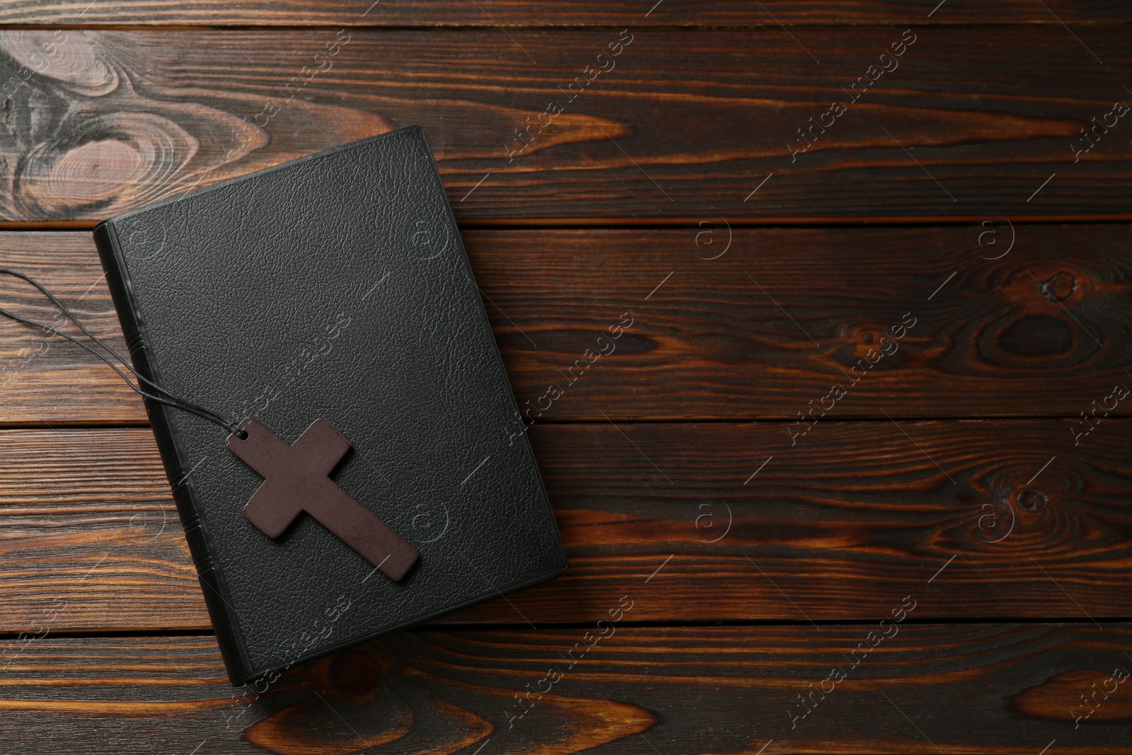 Photo of Wooden Christian cross and Bible on table, top view. Space for text