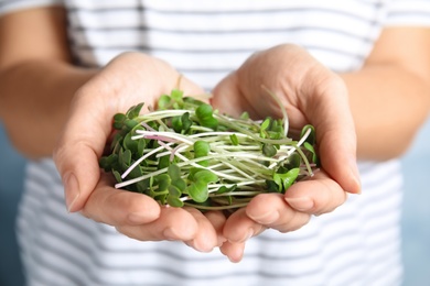 Photo of Woman holding fresh organic microgreen, closeup view