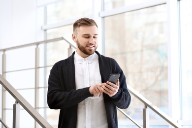 Photo of Portrait of confident young man with mobile phone on stairs