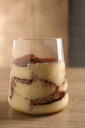 Photo of Delicious tiramisu in glass on wooden table, closeup