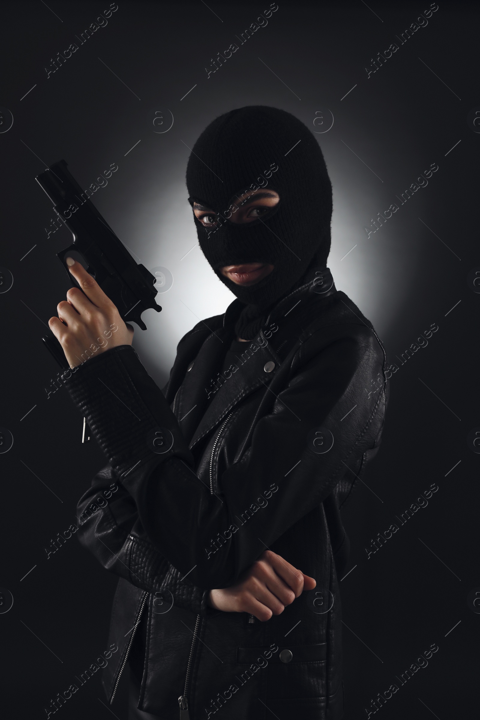 Photo of Woman wearing knitted balaclava with gun on black background