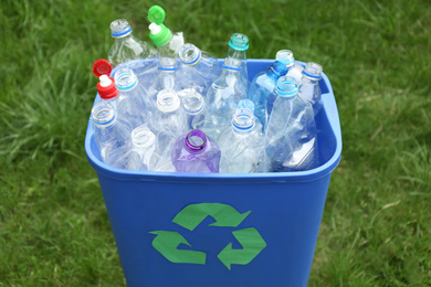 Photo of Many used bottles in trash bin outdoors, closeup. Plastic recycling