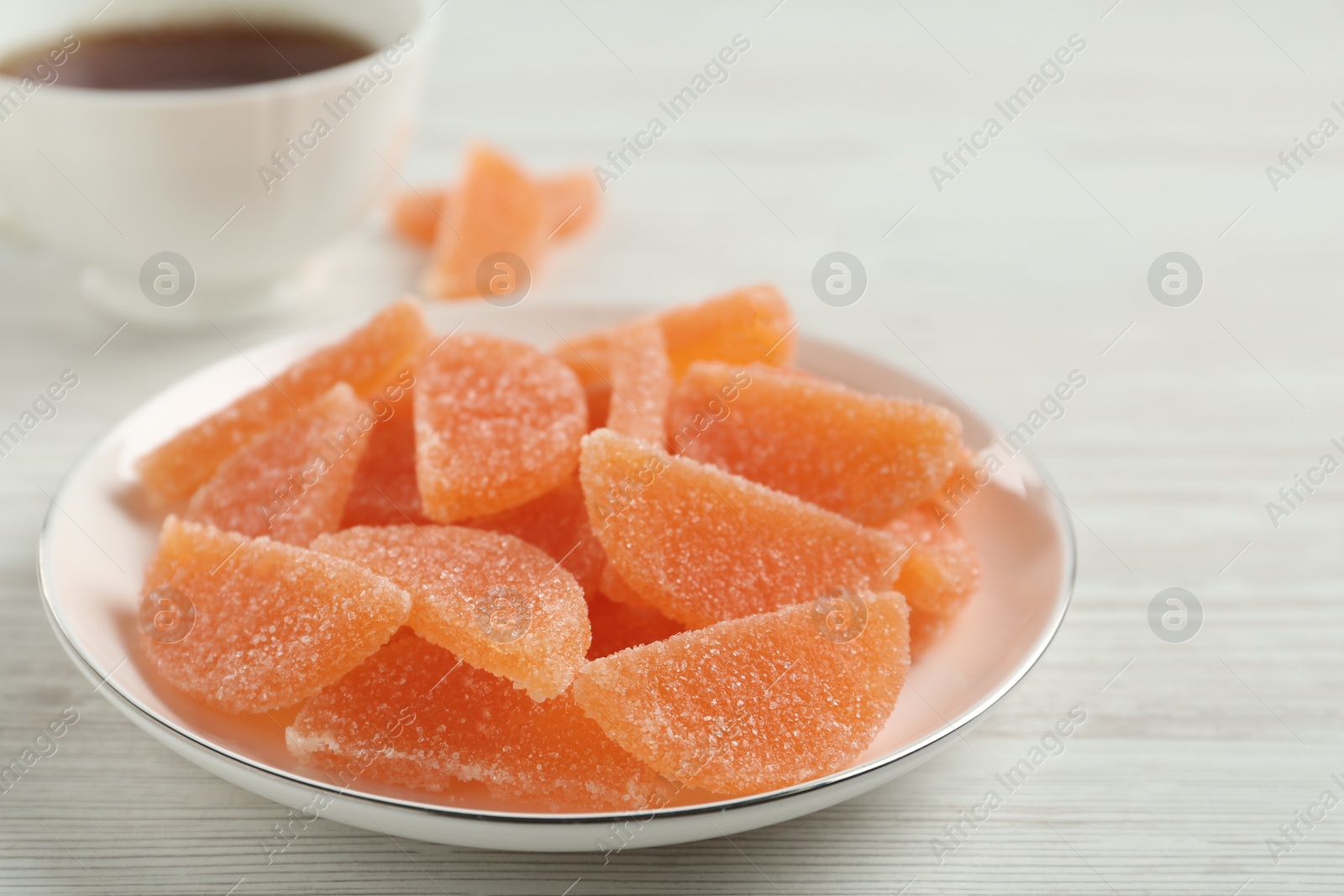 Photo of Tasty orange jelly candies on white table, closeup