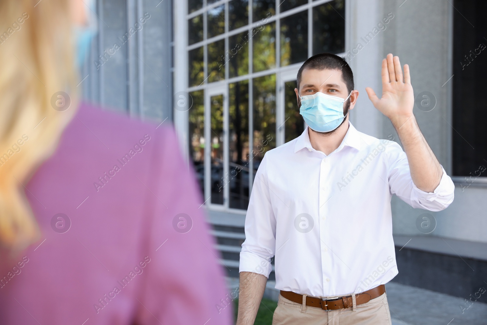 Photo of Man in protective face mask saying hello outdoors. Keeping social distance during coronavirus pandemic