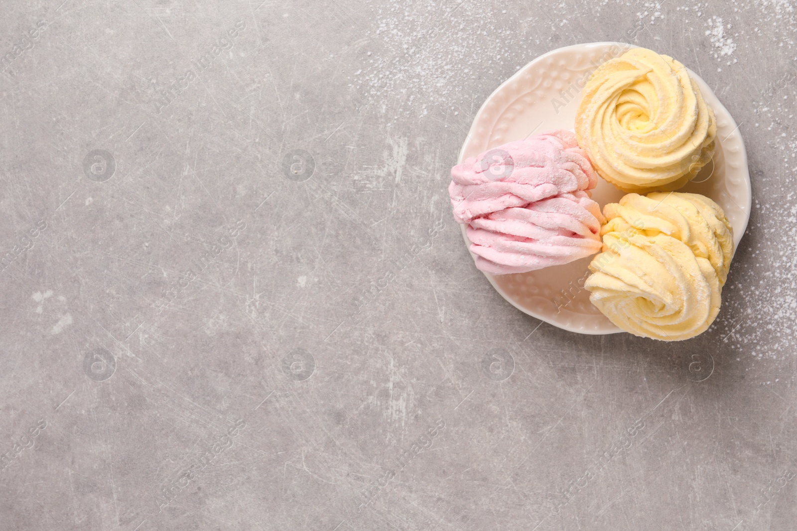 Photo of Delicious pink and yellow marshmallows on grey table, top view. Space for text