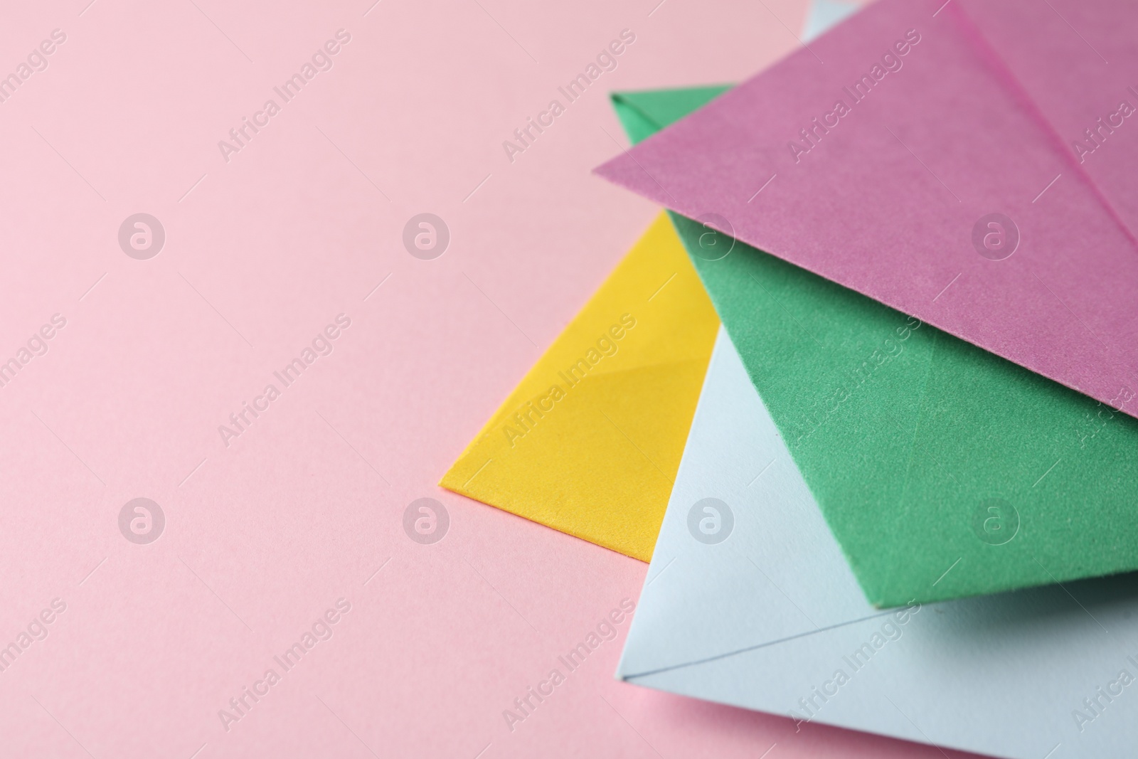 Photo of Colorful paper envelopes on pink background, closeup. Space for text