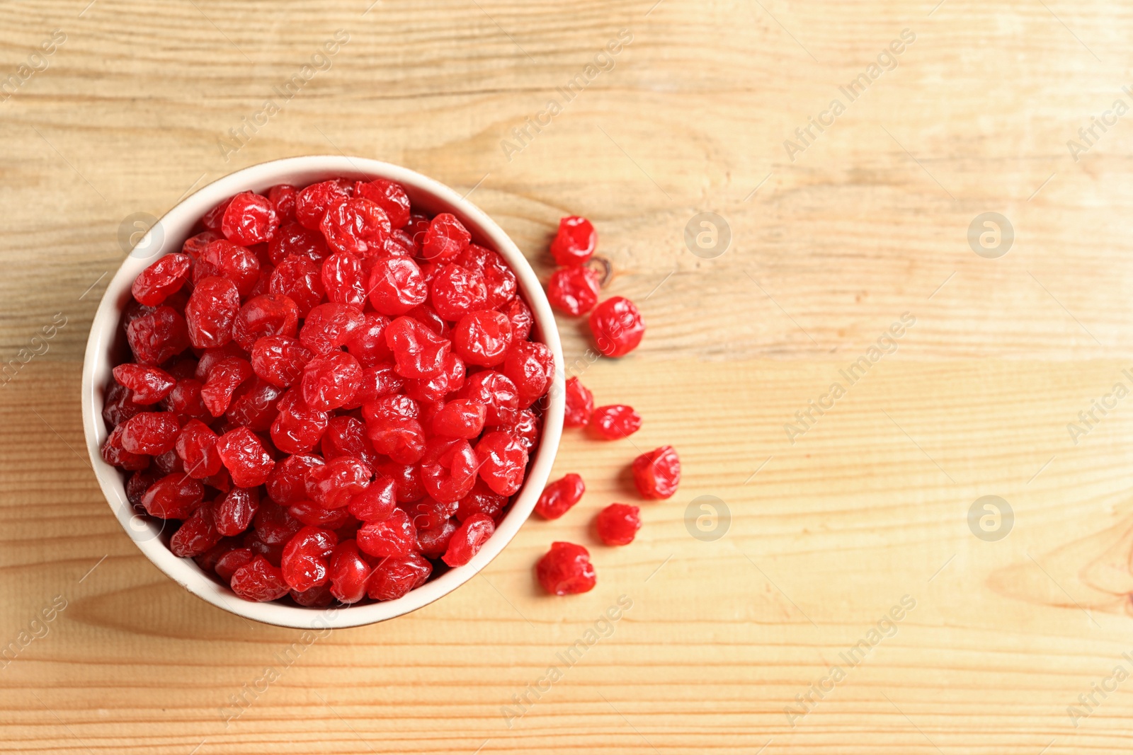 Photo of Bowl of sweet cherries on wooden background, top view with space for text. Dried fruit as healthy snack