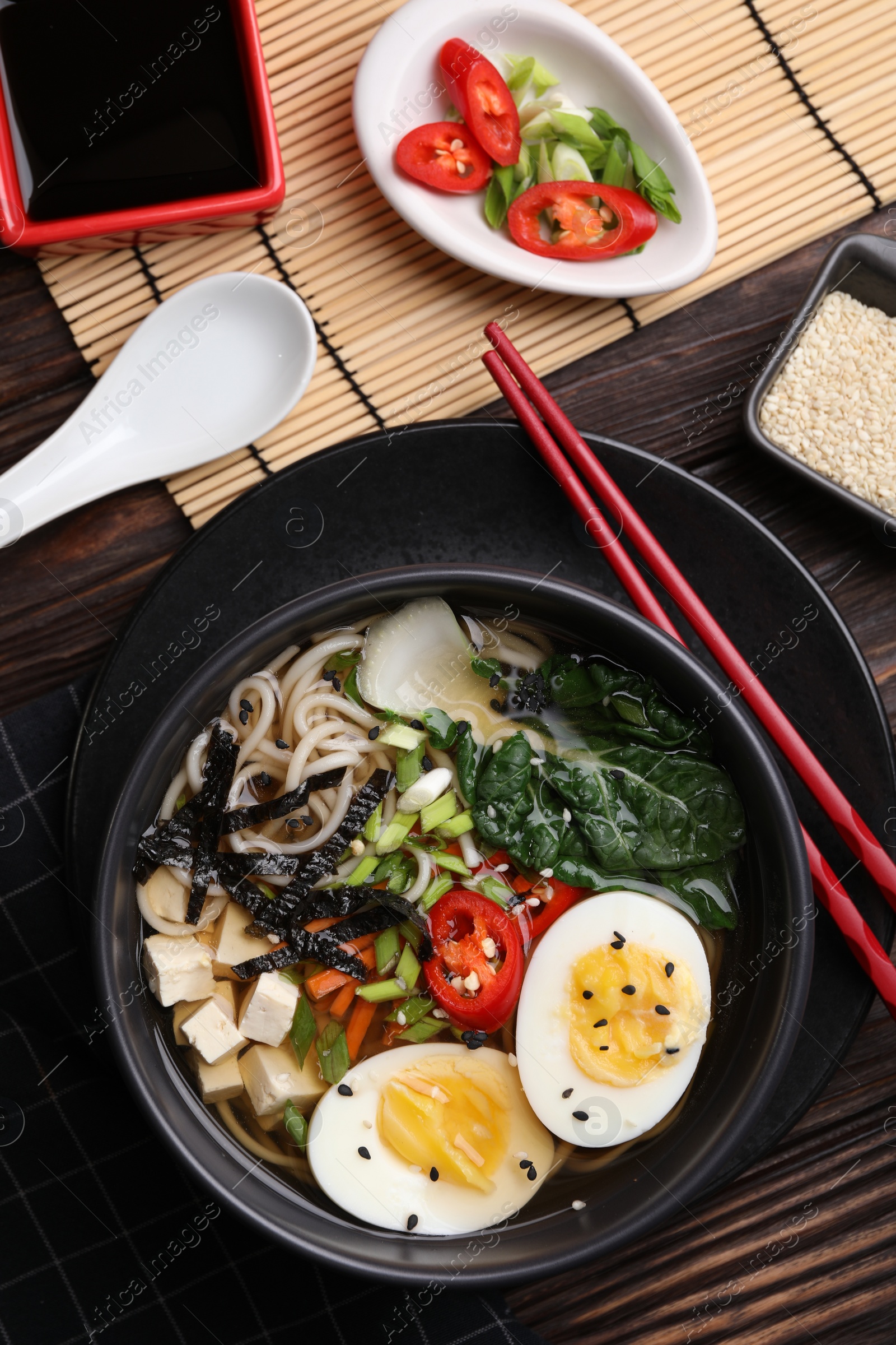 Photo of Delicious vegetarian ramen served on wooden table, flat lay. Noodle soup