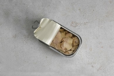 Open tin can of tasty cod liver on textured table, top view
