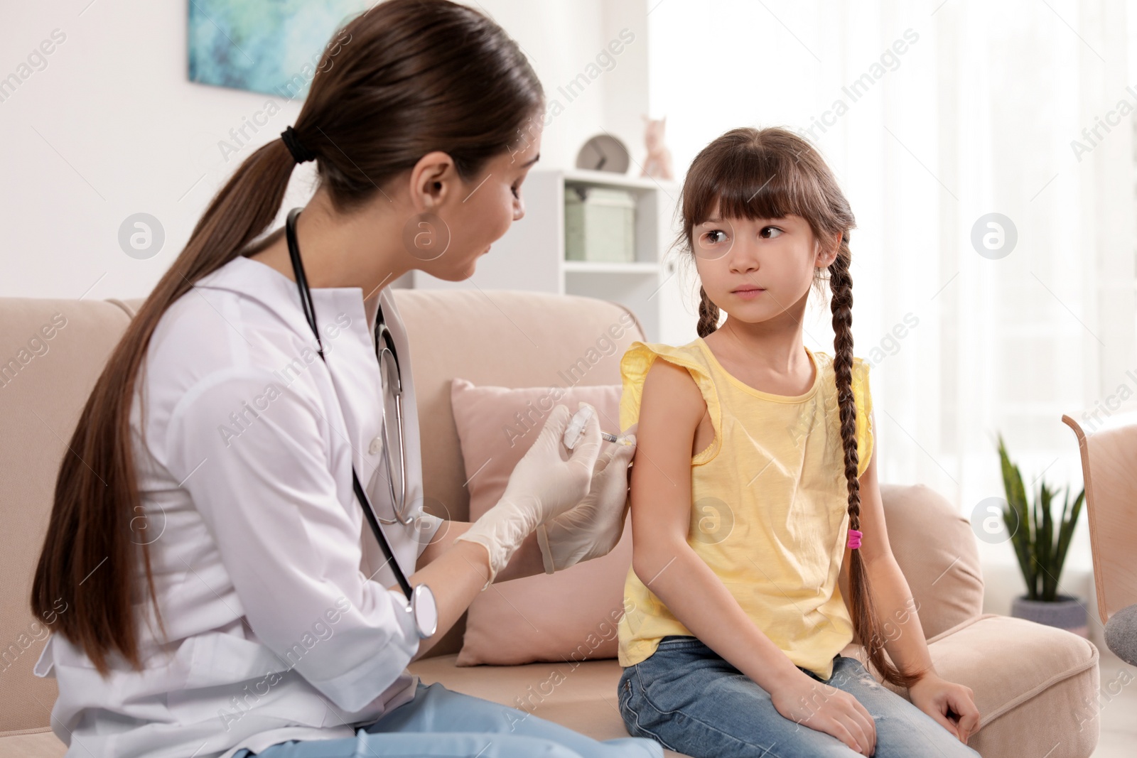 Photo of Family doctor vaccinating little child at home