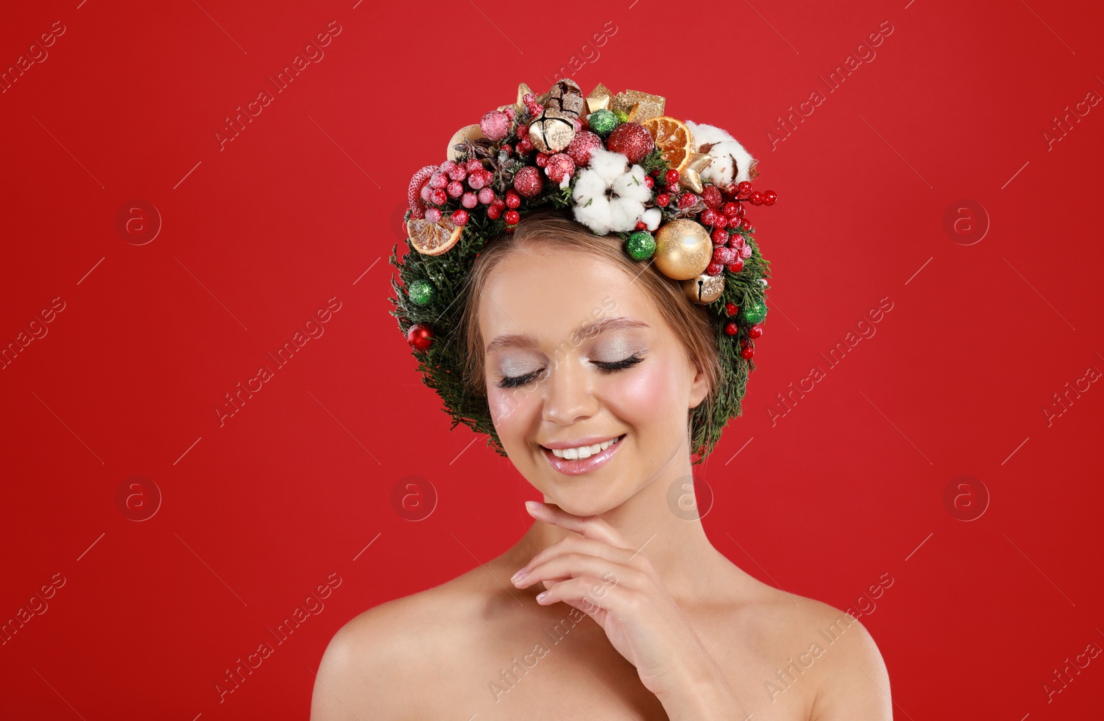 Photo of Beautiful young woman wearing Christmas wreath on red background