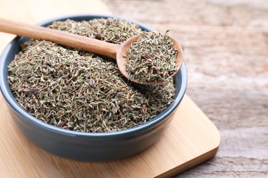 Plate with dried thyme and spoon on wooden table, closeup