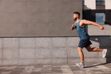 Photo of Smiling man running near building outdoors. Space for text