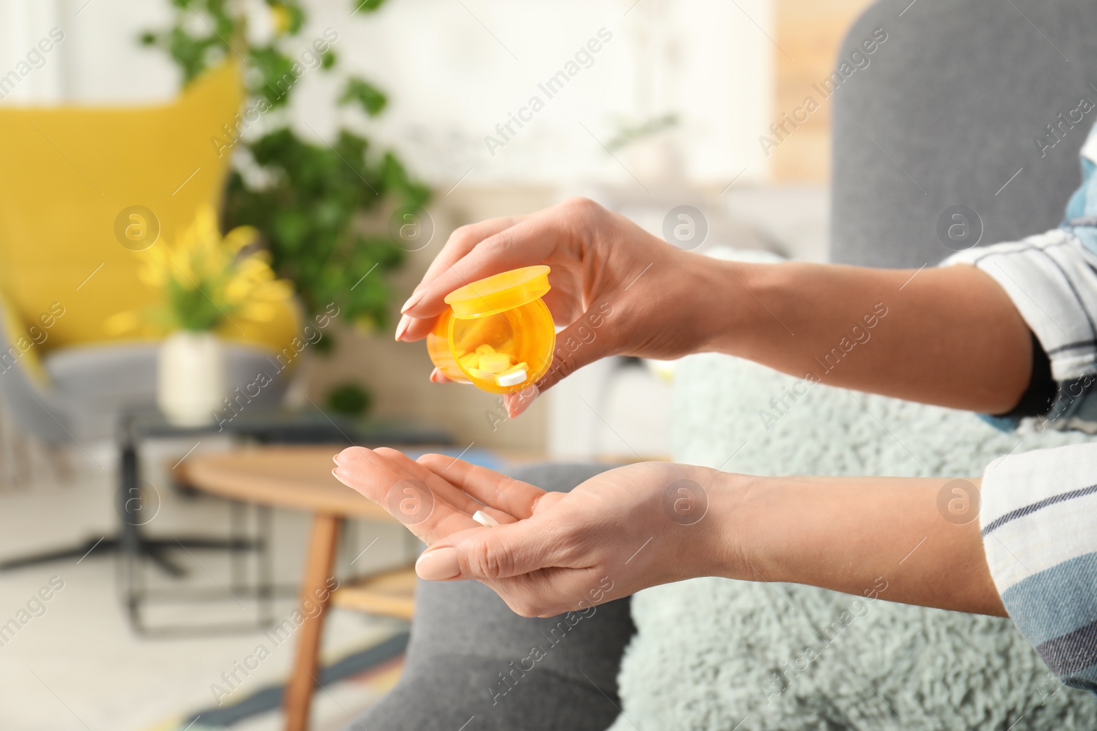 Photo of Woman pouring pills from bottle into hand indoors, closeup