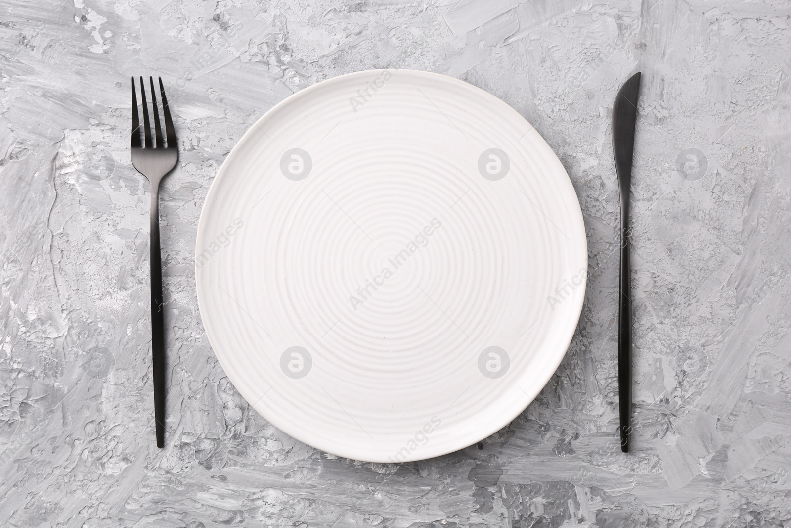 Photo of Elegant setting with stylish cutlery on grey textured table, flat lay