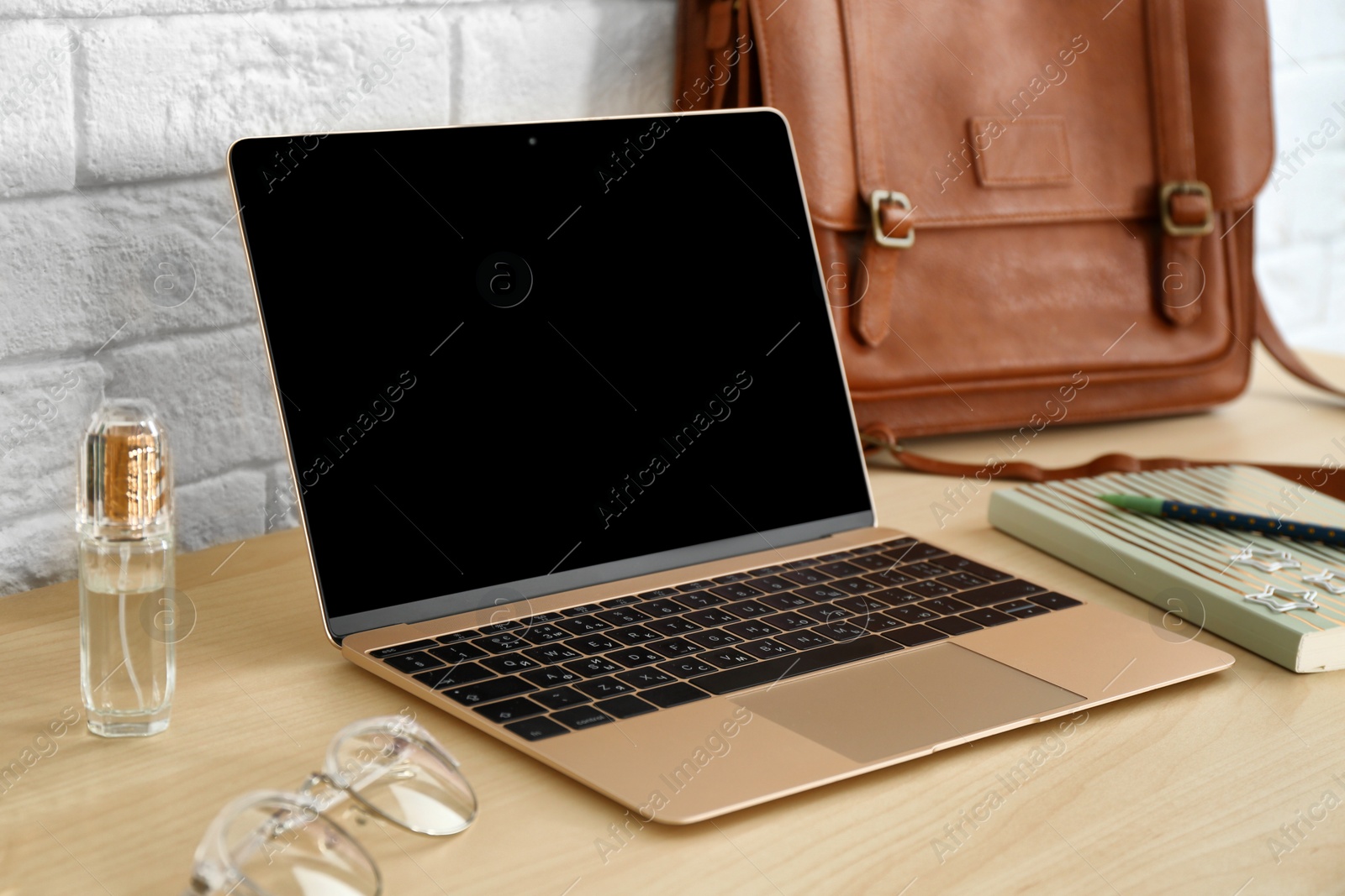 Photo of Stylish workplace with modern laptop on table near brick wall. Fashion blogger