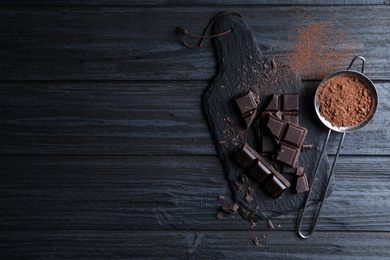 Photo of Flat lay composition with delicious dark chocolate on black wooden table. Space for text