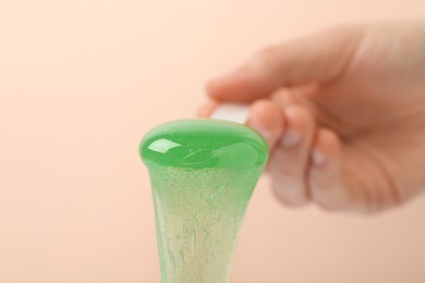 Woman holding spatula with hot depilatory wax on beige background, closeup