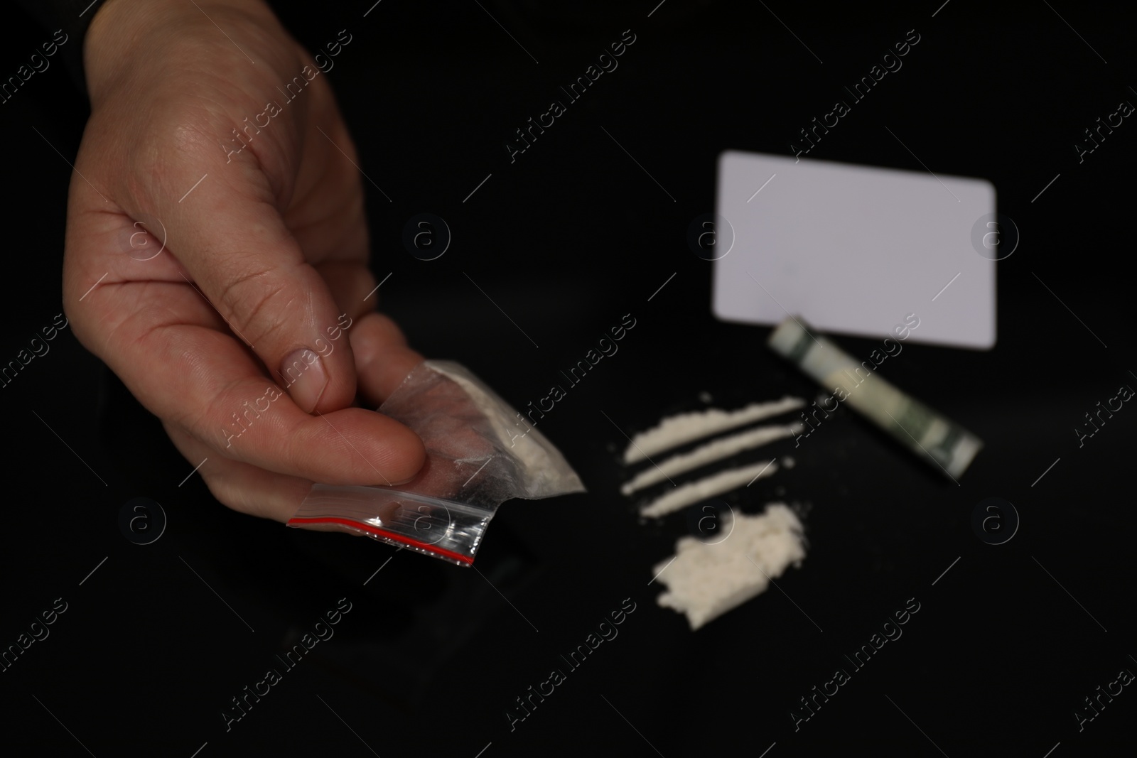 Photo of Drug addiction. Man with cocaine and rolled dollar banknote at black table, closeup