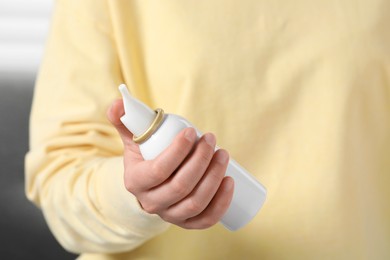 Photo of Woman holding nasal spray indoors, closeup view