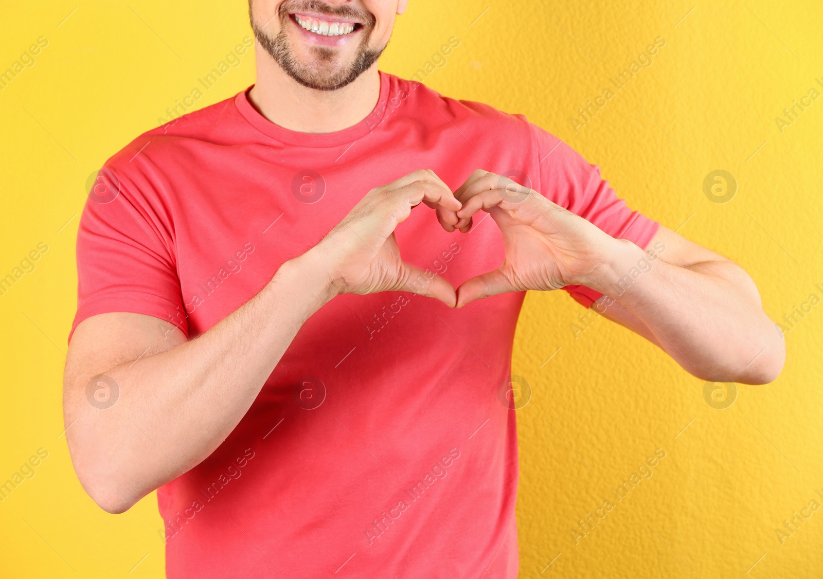 Photo of Man making heart with his hands on color background, closeup