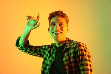 Young man dancing on color background in neon lights