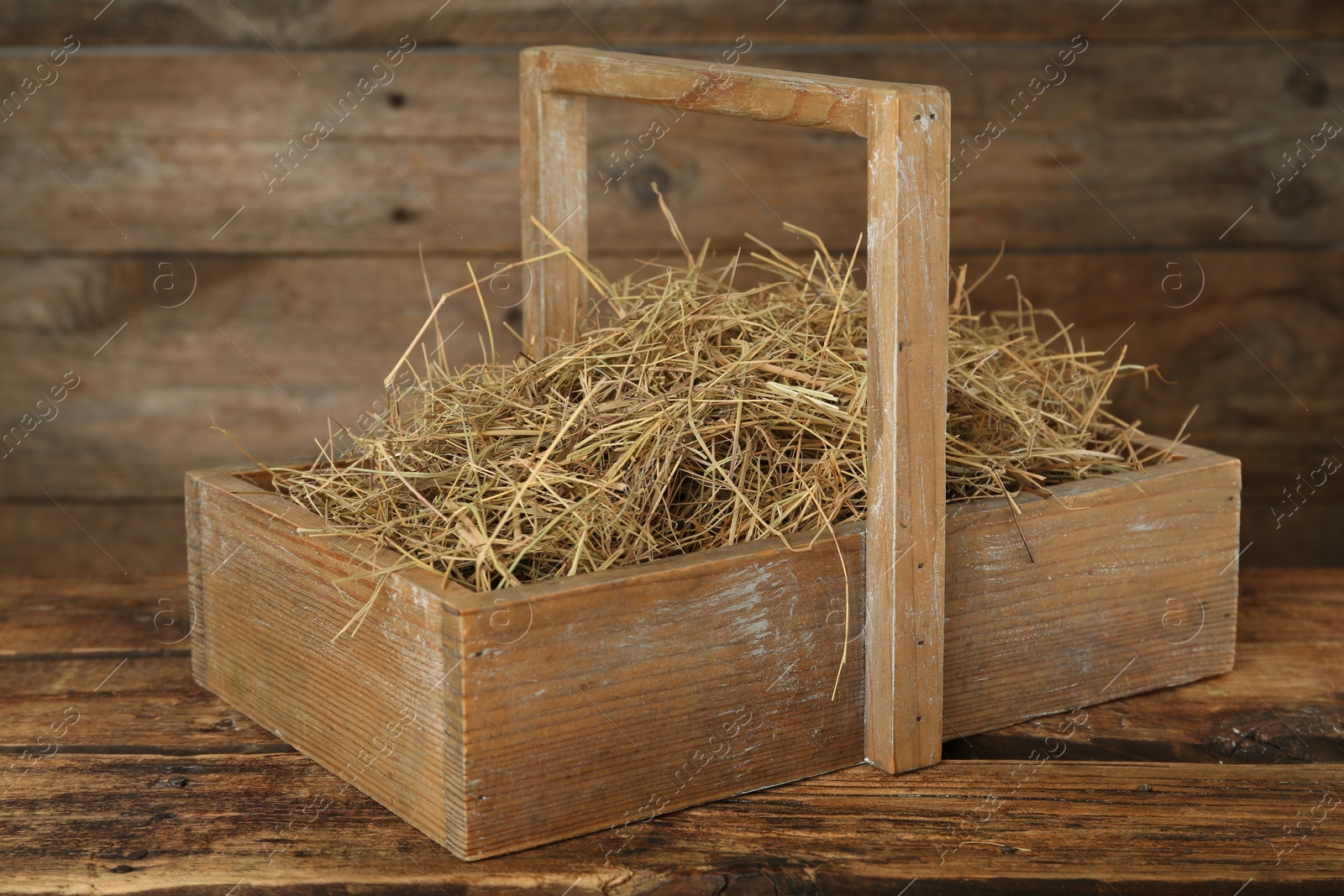 Photo of Dried hay in crate on wooden table