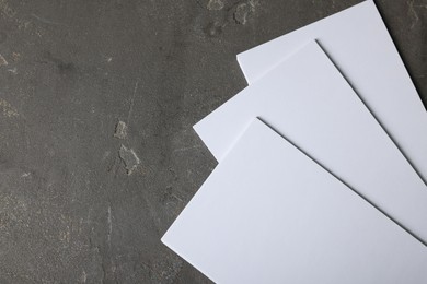 Photo of Blank paper sheets on grey textured background, top view. Mockup for design