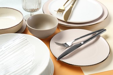 Photo of Clean plates, bowls, glass and cutlery on table