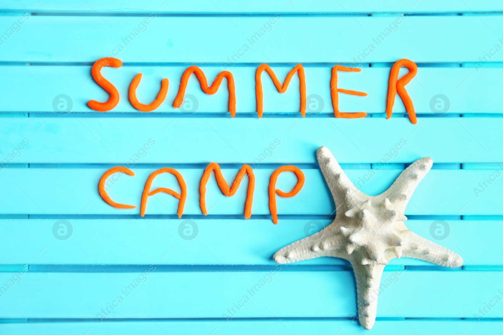 Photo of Flat lay composition with words SUMMER CAMP made from modelling clay and sea star on color background