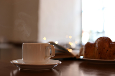 Photo of Delicious morning coffee and croissant served for breakfast on wooden table