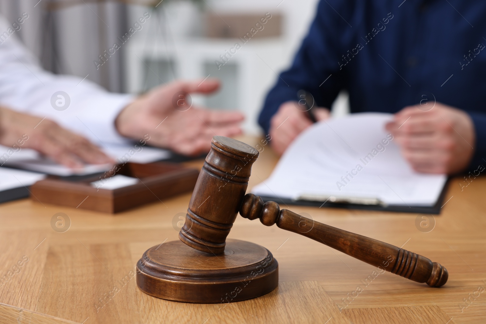Photo of Man signing document in lawyer's office, focus on gavel