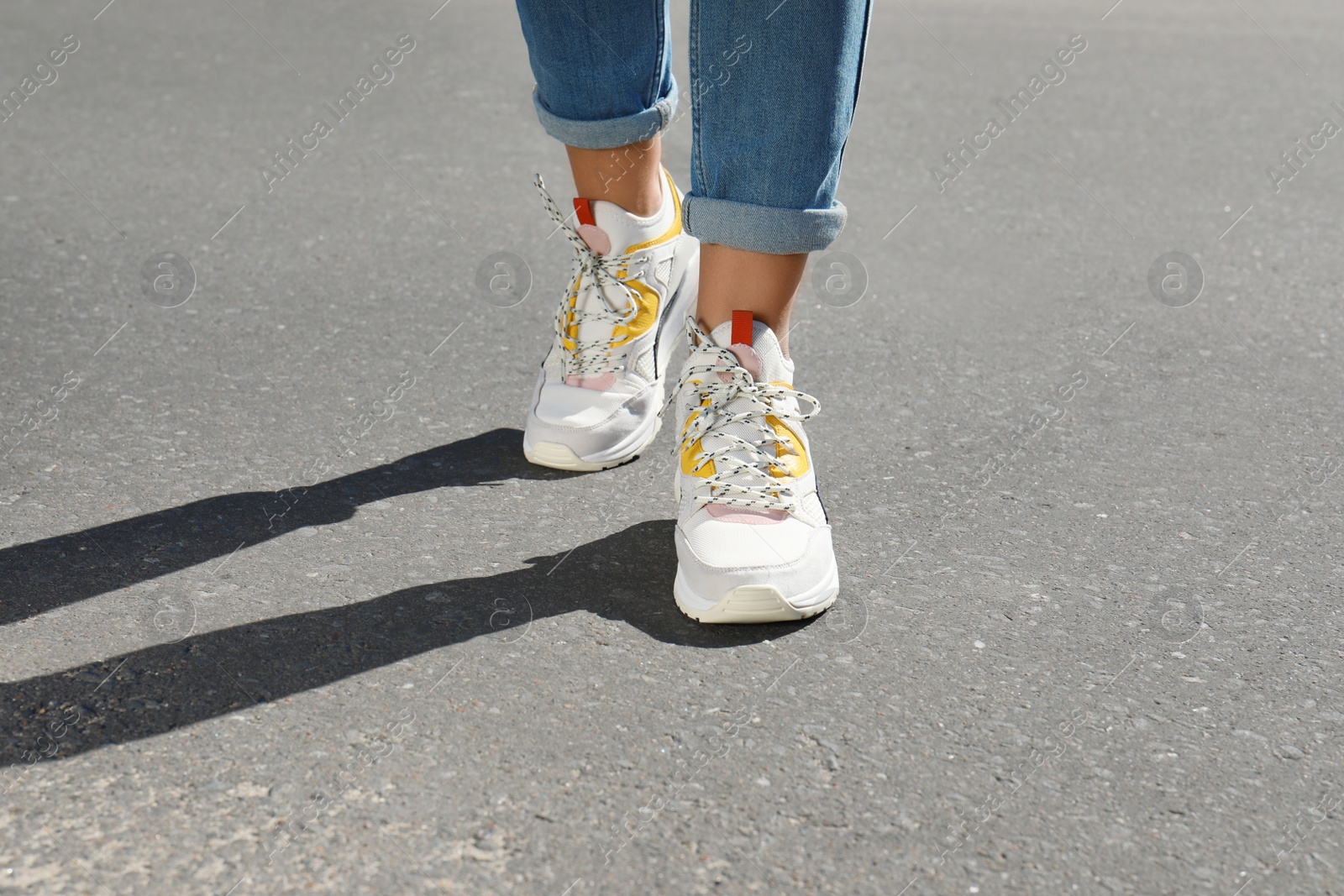 Photo of Woman in stylish sneakers walking outdoors, focus on legs