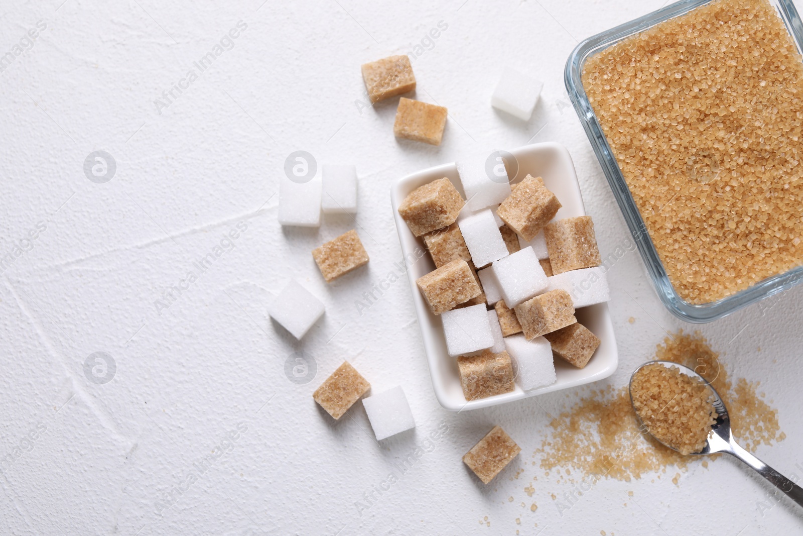 Photo of Bowls and spoon with different types of sugar on white table, flat lay. Space for text