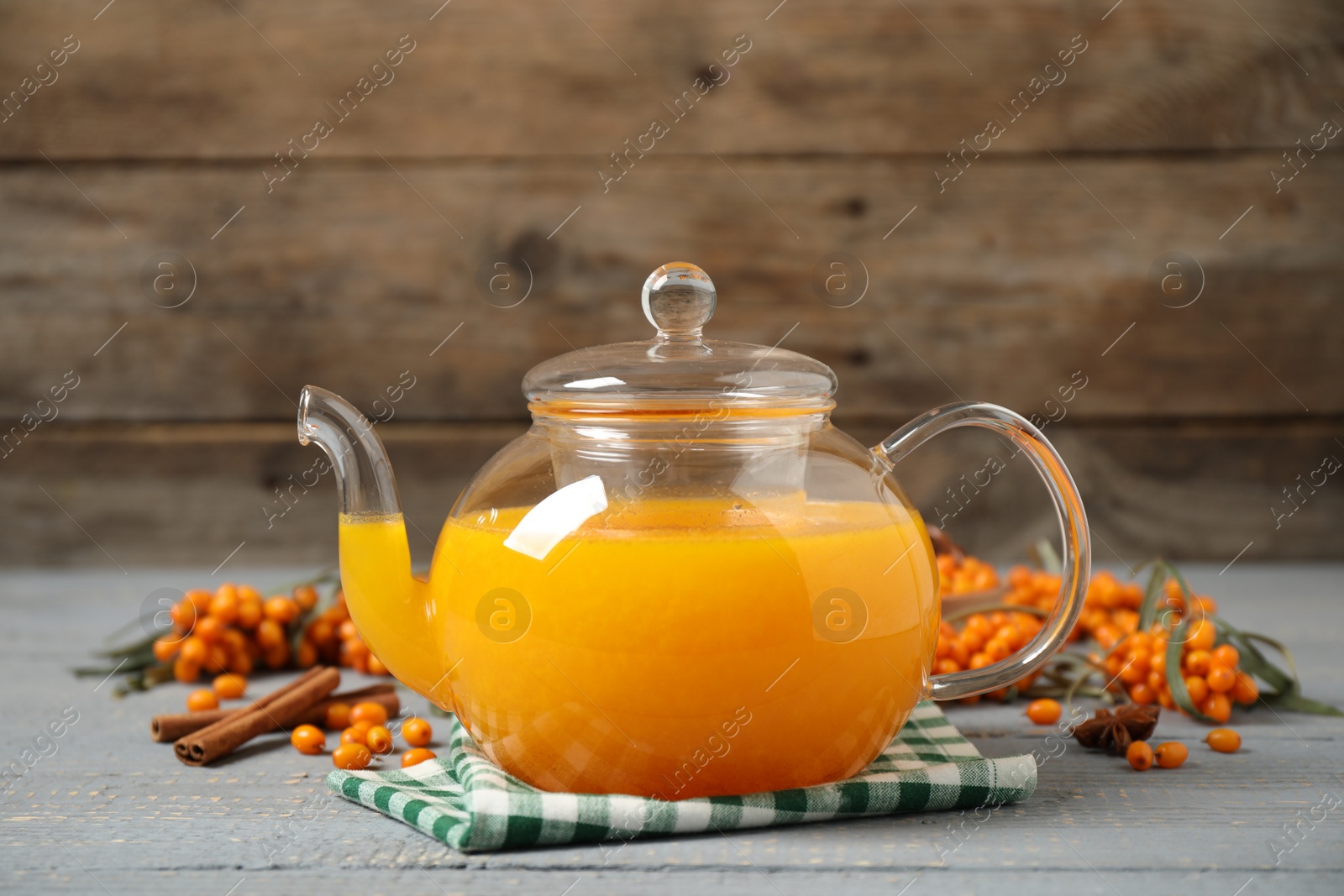 Photo of Delicious sea buckthorn tea, fresh berries and spices on grey wooden table