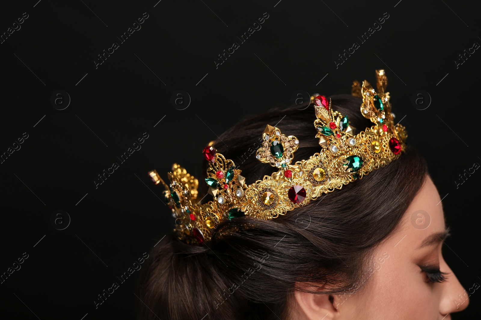 Photo of Beautiful young woman wearing luxurious crown on black background, closeup. Space for text