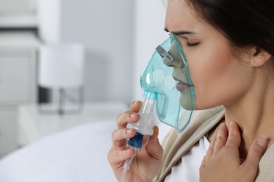 Photo of Sick young woman using nebulizer at home, closeup. Space for text