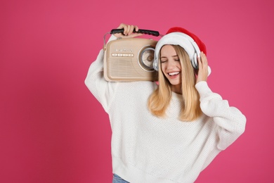 Photo of Happy woman with vintage radio and headphones on pink background. Christmas music
